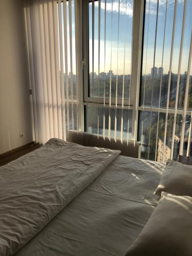 Bett in einem Zimmer mit einem großen Fenster in der Unterkunft Apartmant in Smart Plaza in Kiew