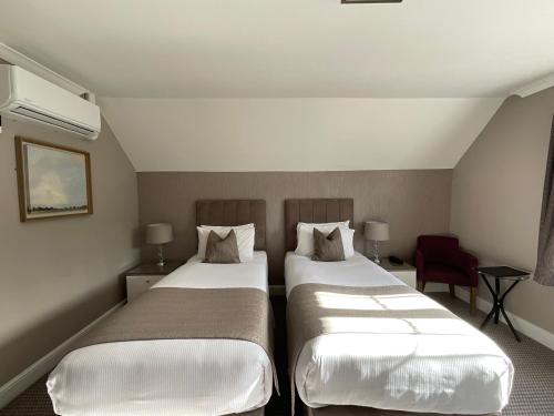 a hotel room with two beds and a red chair at The Riverside in Salisbury