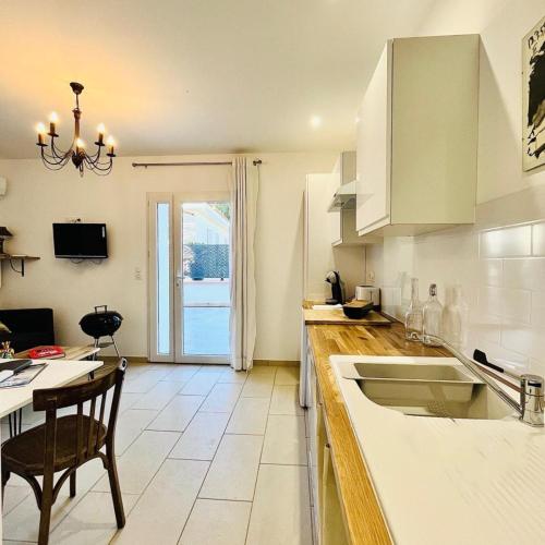 a kitchen with a sink and a table with a chair at LE FIGUIER in Cabestany