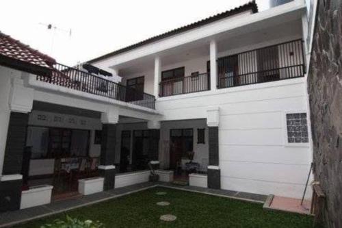 a white building with a balcony and a yard at OYO Life 93158 Kost Asaka in Serang