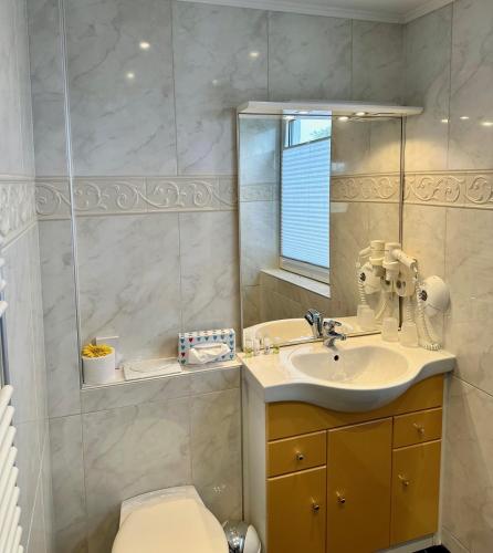 a bathroom with a sink and a toilet and a mirror at Aparthotel Kleine Perle in Cuxhaven