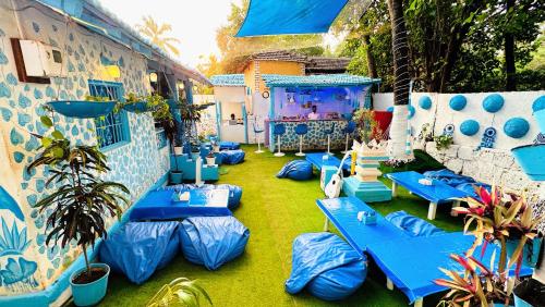 un patio con mesas azules y una pantalla grande en Omkar wellness inn en Arambol