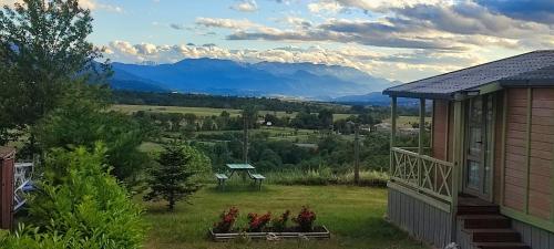 une maison fleurie dans une cour avec des montagnes en arrière-plan dans l'établissement Le petit Chalet de Saillagouse - Location tout confort à la montagne, à Saillagouse