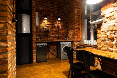a kitchen with a brick wall and a table and chairs at HOUSEHOST ApartmenI: Podbrzezie 2/20 in Krakow