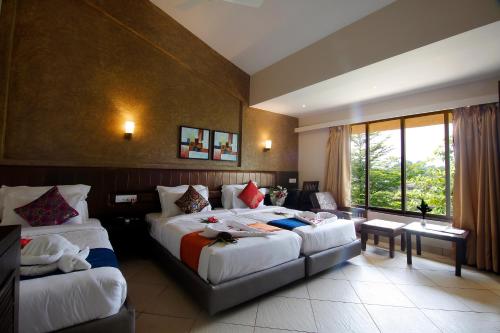 a hotel room with two beds and a couch at Misty Meadows, Lonavala in Lonavala