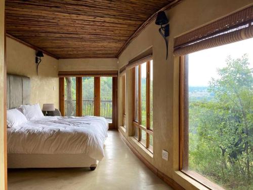 a bedroom with a bed and large windows at Reedbuck Lodge @Cyferfontein in Mabalingwe Reserve in Bela-Bela