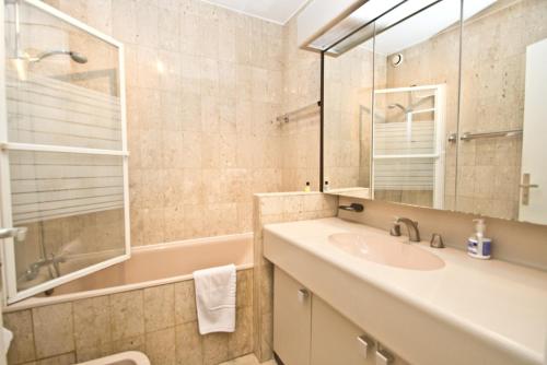 une salle de bain avec un lavabo, une baignoire et un miroir dans l'établissement GRAY 2a6, à Cannes