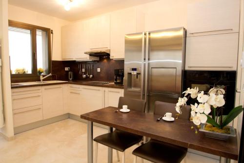 La cuisine est équipée d'une table en bois et d'un réfrigérateur en acier inoxydable. dans l'établissement GRAY 2a7, à Cannes
