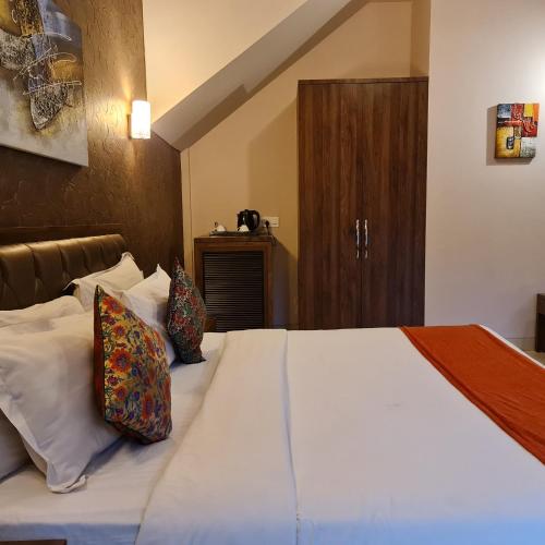 a bedroom with a bed with white sheets and pillows at Misty Meadows, Lonavala in Lonavala