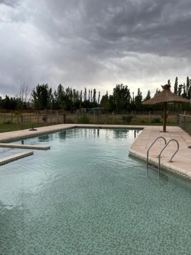 a large swimming pool with an umbrella in a yard at Posada Villa Pituil in Barreal