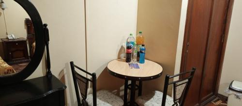 Una mesa pequeña con dos sillas y botellas. en Hotel el LUCERO, en Oruro