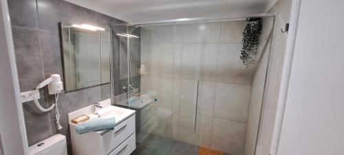 een badkamer met een wastafel en een douche met een spiegel bij Casa jablillo 2 in Costa Teguise