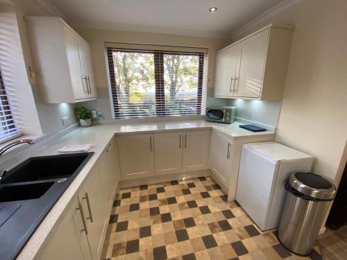 a kitchen with white cabinets and a checkered floor at The Lodge at Woodend in Kemnay