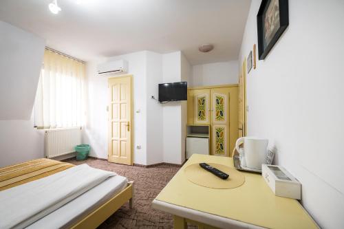 a bedroom with a bed and a table with a remote control at Hotel Sugas in Sfântu-Gheorghe