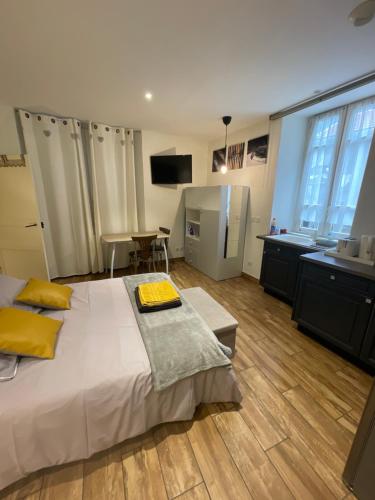 a bedroom with a large white bed and a kitchen at la Montagnette les marmottes STUDIO maison en travaux de 10h a 17h in Moutiers