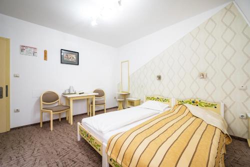 1 dormitorio con 1 cama, mesa y sillas en Hotel Sugas en Sfântu-Gheorghe