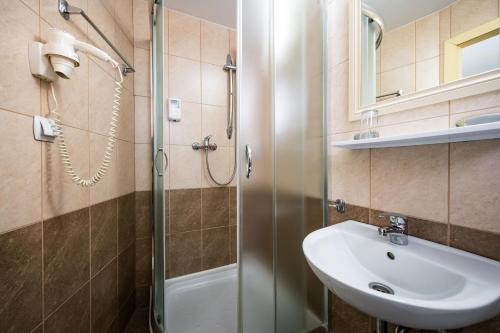 a bathroom with a sink and a shower at Hotel Sugas in Sfântu-Gheorghe