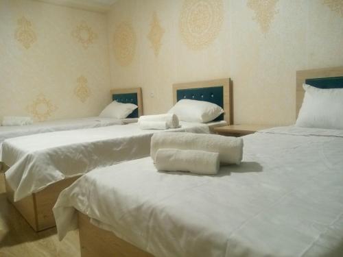 a room with three beds with white sheets at Elita House Samarkand in Samarkand