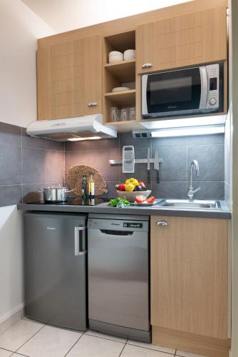 a kitchen with a sink and a microwave at Résidence Pierre & Vacances Premium Le Domaine de Cramphore in Le Pouliguen