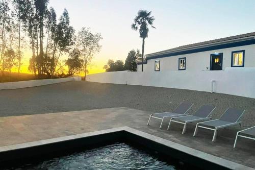 two chairs and a pool in a patio with a building at Monte da Falagueira by Portus Alacer in Arronches
