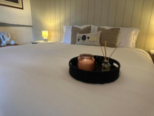 Una vela en una bandeja sentada encima de una cama en Woolpack Inn, en Canterbury