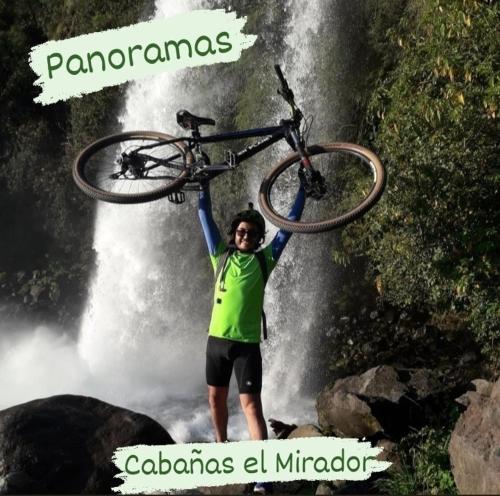 a man holding a bike on top of a waterfall at Cabañas el Mirador in Recinto