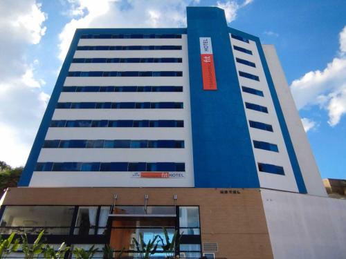 un grand bâtiment bleu et blanc avec un panneau rouge sur lui dans l'établissement Transamerica Fit Lafaiete, à Conselheiro Lafaiete