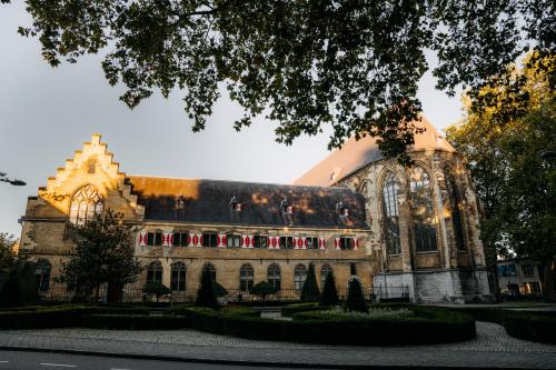 duży kamienny budynek z drzewem przed nim w obiekcie Kruisherenhotel Maastricht - Oostwegel Collection, member of Design Hotels w mieście Maastricht