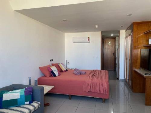 a bedroom with a red bed and a couch at Flat no mar da baía de T. Santos in Salvador