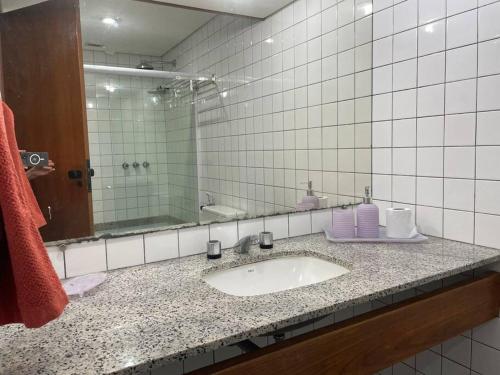 uma casa de banho com um lavatório e um espelho em Flat no mar da baía de T. Santos em Salvador