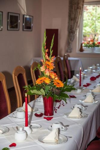 a long table with a vase of orange flowers on it at Hotel Zum Stern Spreewald in Werben