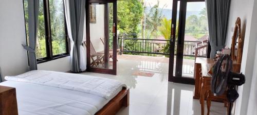 a bedroom with a bed and a balcony with windows at Giri Swari Homestay in Sidemen