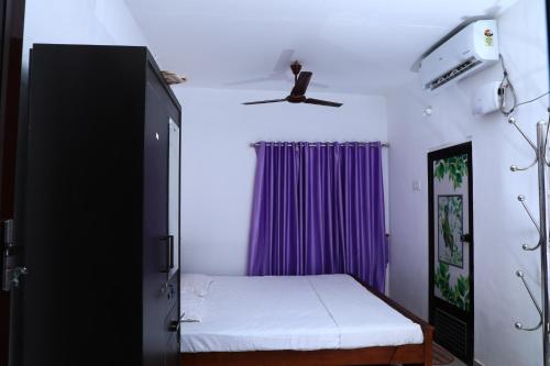 a bedroom with a bed and a purple curtain at Ashtaman's Chayakkadaveedu Homestay in Munroe Island
