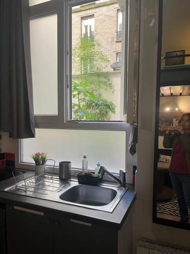 a kitchen sink and a window in a kitchen at Charmant studio fonctionnel in Paris