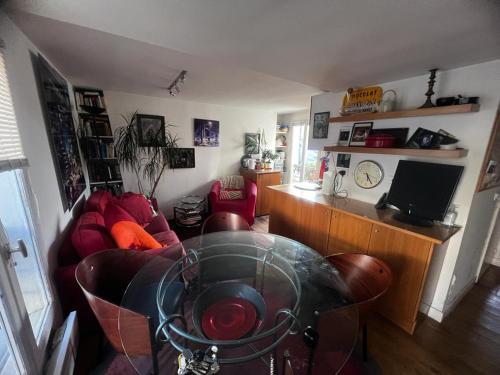 un salon avec un canapé rouge et une table en verre dans l'établissement Appartement - Belle vue - Marais, à Paris