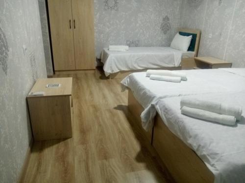 a room with two beds with white sheets and wooden floors at Elita House Samarkand in Samarkand