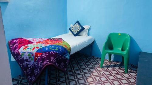 a small bedroom with a bed and a green chair at Mayur Guest House in Pushkar