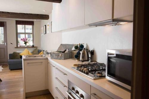 1700 Period Cottage George Street Addingham في Addingham: مطبخ مع موقد فرن علوي بجوار أريكة