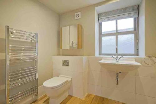 a bathroom with a toilet and a sink and a window at 1700 Period Cottage George Street Addingham in Addingham