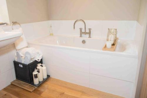 a white bathroom with a sink and a bath tub at The Old Middle School Addingham in Addingham