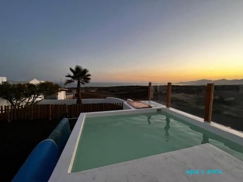 una piscina con puesta de sol en el fondo en CASA TIE' Lanzarote vista mar - piscina relax - adults only, en Tías