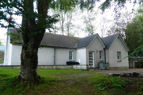 une maison blanche avec un arbre devant dans l'établissement River Cottage, à Turriff