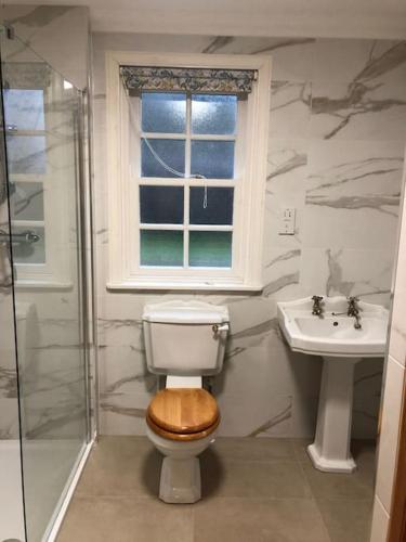 a bathroom with a toilet and a sink and a window at River Cottage in Turriff