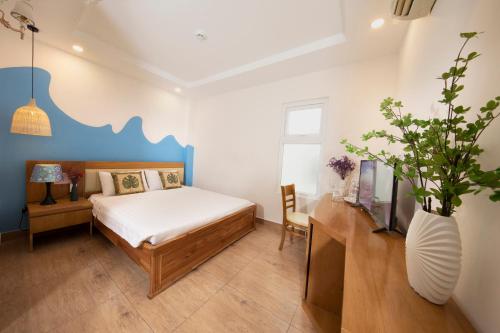 um quarto com uma cama e um vaso com uma planta em Summer Beach Hotel Vung Tau em Vung Tau