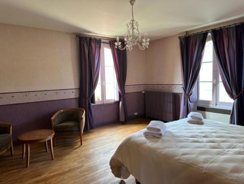 um quarto com uma cama, 2 cadeiras e um lustre em La Ferme de l'Abbaye em Silli-en-Gouffern