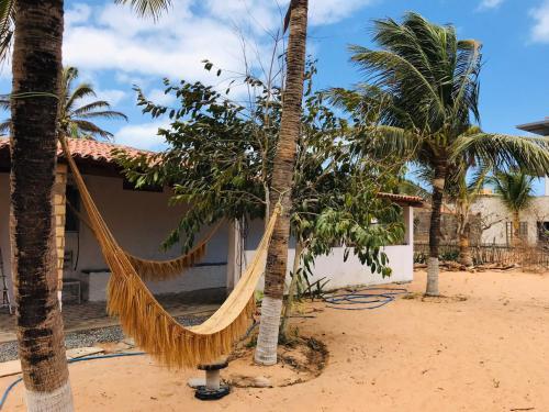 a hammock between two palm trees in front of a house at Hostel Jericoacoariano in Jericoacoara
