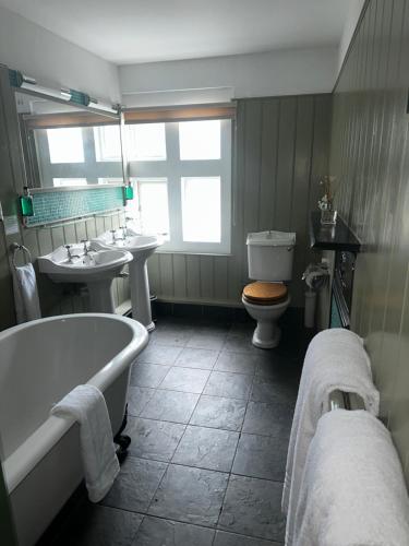 een badkamer met 2 wastafels, een bad en een toilet bij Woolpack Inn in Canterbury