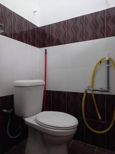 a bathroom with a toilet and a yellow hose at Bilik Transit Nilai in Nilai