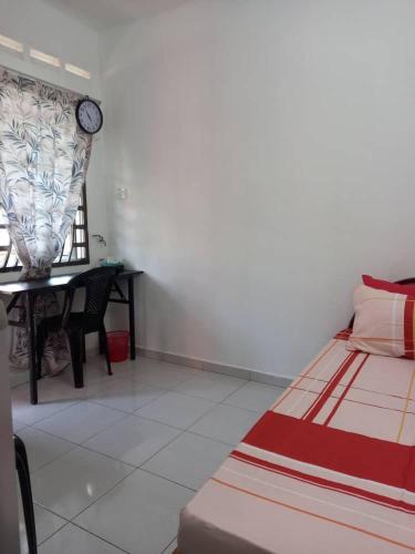 a bedroom with a bed and a table with a clock on the wall at Bilik Transit Nilai in Nilai