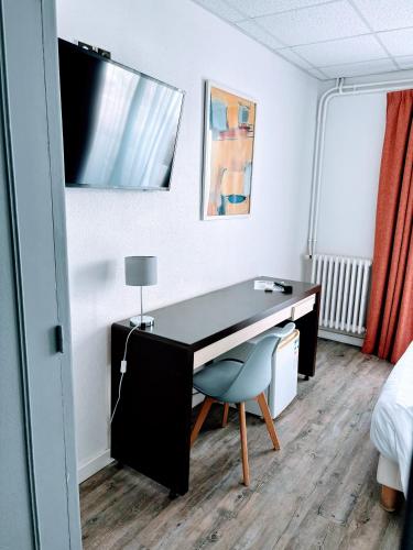 a room with a desk and a chair and a bed at Brasilia Hôtel in Palavas-les-Flots